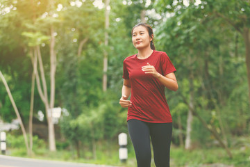 Front of woman runner and runing at the road surround with green forest.
