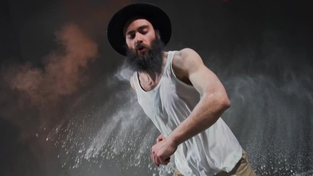 Man dancer showing break-dancing moves against colourful powder explosion