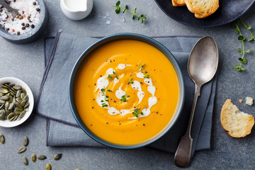 Pumpkin and carrot soup with cream on grey stone background. Top view. - 302220176