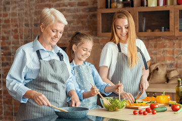 Three female generation cooking healthy dinner together