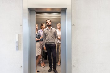 Business people waiting in elevator - obrazy, fototapety, plakaty