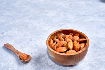 Almonds in brown bowl on wooden background