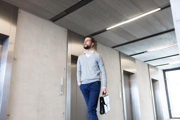 Low angle view of businessman walking against elevator in office
