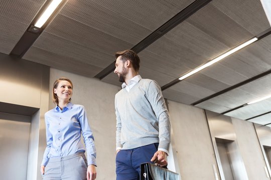 Business people walking against elevator in office