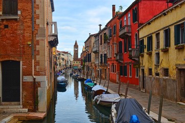 Fototapeta na wymiar quiet street along the narrow Venetian canal overlooking the ancient tower