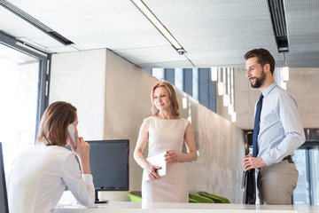 Fototapeta premium Receptionist calling manager while business people waiting in office lobby