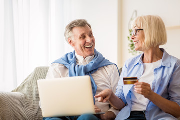Modern mature couple shopping online on laptop