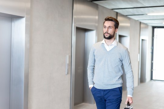 Businessman walking against elevator in office