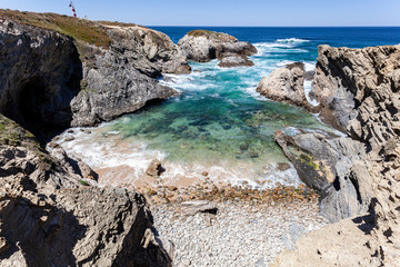 Beautiful beach with round stones, protected from the waves by rocks in the fishermen's route in the Alentejo, Portugal, Europe.