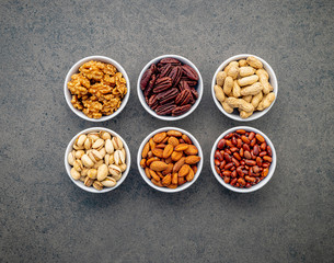Mixed beans and nuts in the white bowl on brown dark stone background.