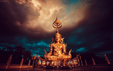 Buddha statue in Thailand temple on background dramatic cloudy sky. Asian culture and religion