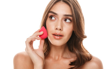 Portrait of charming young half-naked woman applying makeup with sponge