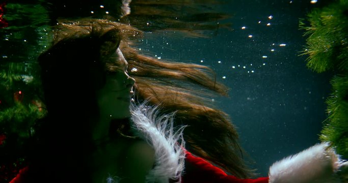 magic atmosphere shot with woman floating under water, looking at christmas tree