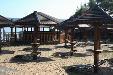 Wooden sunbeds and umbrellas on a deserted beach in low season.