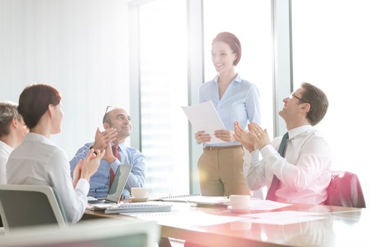 Business people applauding after colleague presentation in office