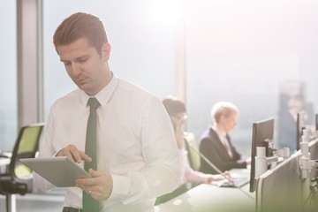 Businessman standing against colleagues working in office