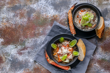 Soup with snow crab meat, udon noodles and vegetables. Serving on a gray napkin and a rusty...