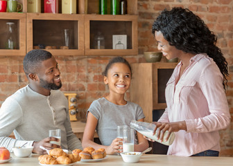 Little girl having breakfast with parents in kitchen