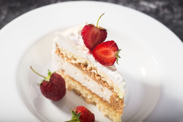 a piece of delicate cake, with slices of sliced strawberries, on a white plate on a white and gray background