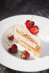 a piece of delicate cake, with slices of sliced strawberries, on a white plate on a white and gray background