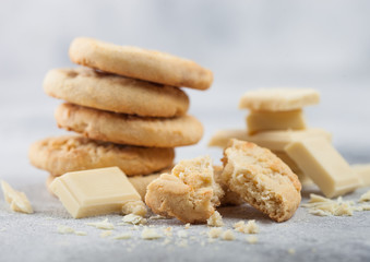 White chocolate biscuit cookies with chocolate blocks and curls on light kitchen table background.