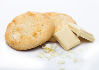 White chocolate biscuit cookies with chocolate blocks and curls on white background.