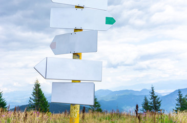 Blank signpost in mountains with beautiful blue sky and clouds.