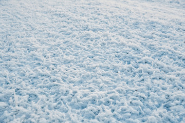 Snow covered frozen grass. White winter texture, top down view.