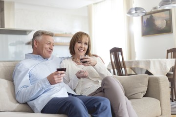 Smiling mature couple sitting on sofa while holding wineglasses at home