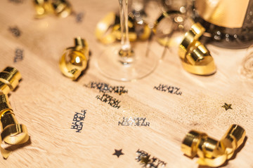 New Year's Eve background with champagne bottle and glasses confetti and gold snakes New Year's Eve background with confetti and gold snakes on wooden table, lights