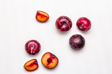 Ripe large purple plums. Fresh whole fruits, half sliced, seeds. Isolated on white background