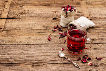 Hot hibiscus tea. Dry petals, linen sacks. Healthy food and self-care concept. Old wooden boards backgrounds © FuzullHanum