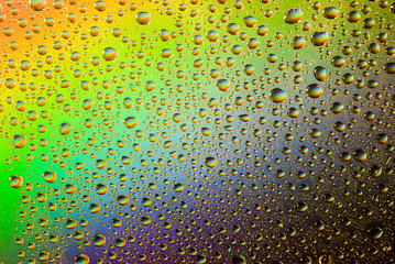 closeup of water droplets on a glass. Rainbow background, colorful abstract pattern.