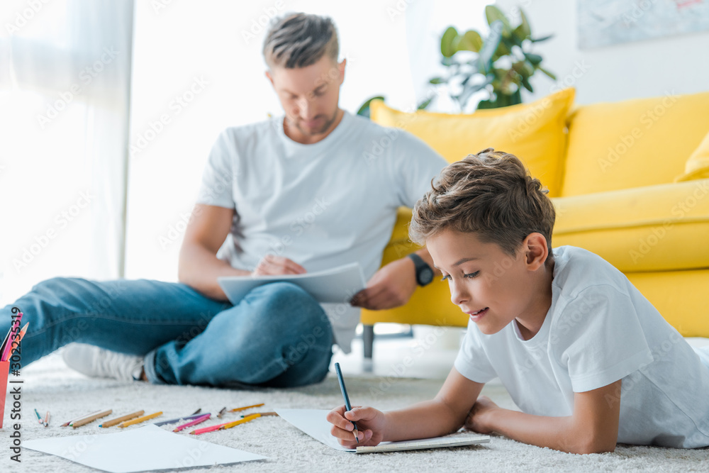 Poster selective focus of happy kid drawing near handsome father at home