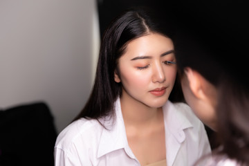 Fototapeta premium Beautiful young asian woman and professional makeup artists applies eye shadow. Beautiful woman face. Perfect makeup.