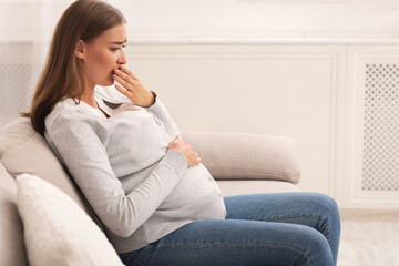 Pregnant Woman Touching Mouth Feeling Sick Sitting On Couch Indoor