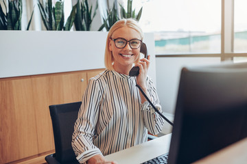 Smiling businesswoman sitting at her desk talking on a telephone