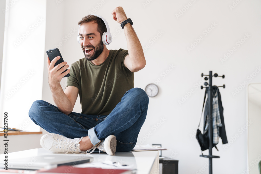 Canvas Prints Image of young man listening music with headphones and using cellphone