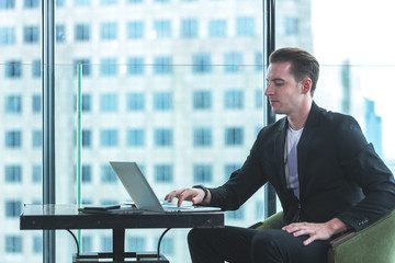 Fototapeta premium Businessman using tablet computer to work with financial data in the modern office, relax and rest time after work. City background. Business Concept.
