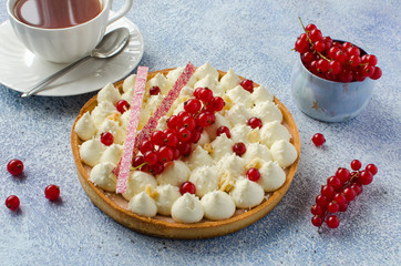 Homemade tart with coconut cream and red currant on blue background