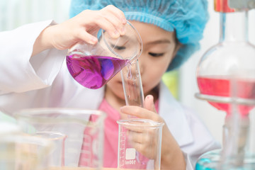 Asian little girl playing with fun as a scientist working in a lab equipped with colored glass tubes.