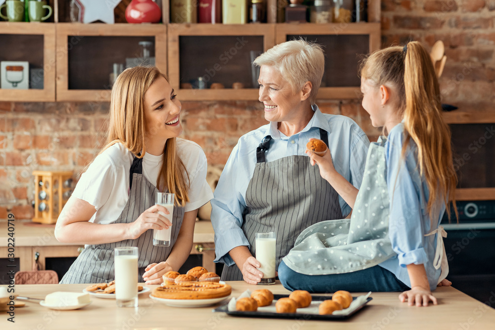 Wall mural daughter, mother and grandmother tasting fresh cupcakes at kitchen