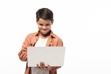 Fototapeta premium concentrated boy using laptop while standing isolated on white