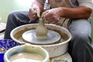 Male hands working on a potter wheel closeup. Making dishes from clay.