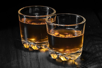 two glasses of cognac on a black tree