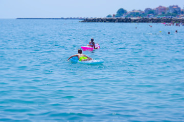 Children swim on an air mattress in the sea