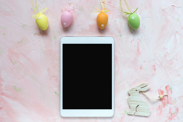 Multicolored eggs decoration and tablet on a pink background. Easter concept.