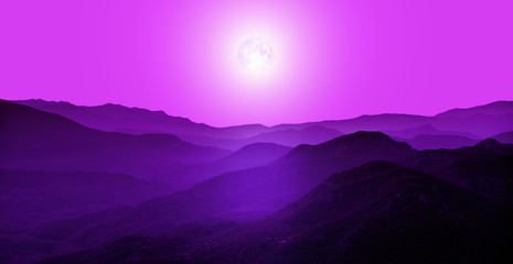 Beautiful landscape with violet misty silhouettes of mountains against shiny full moon "Elements of this image furnished by NASA"