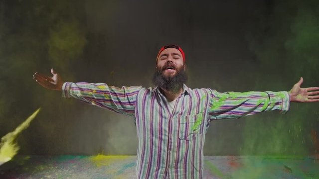 Man dancer showing break-dancing moves against colourful powder explosion.