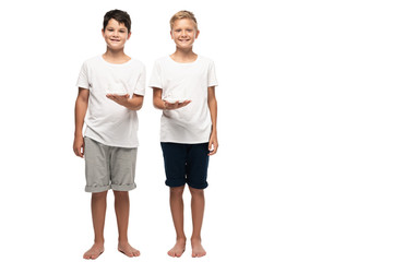 two smiling brothers looking at camera while holding coffee cups on white background